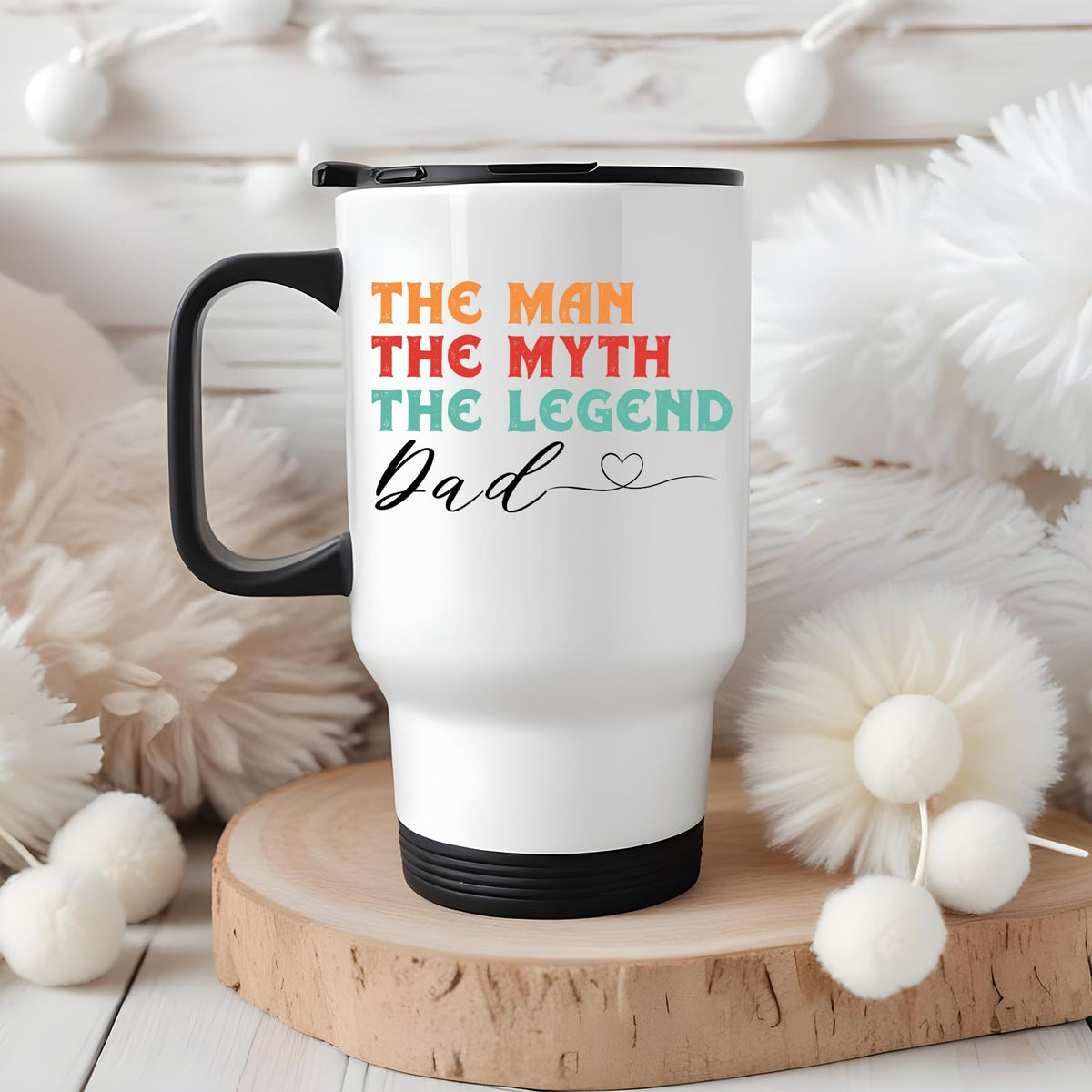 The Man the Myth Dad travel mug on a wooden slice with white pom-poms