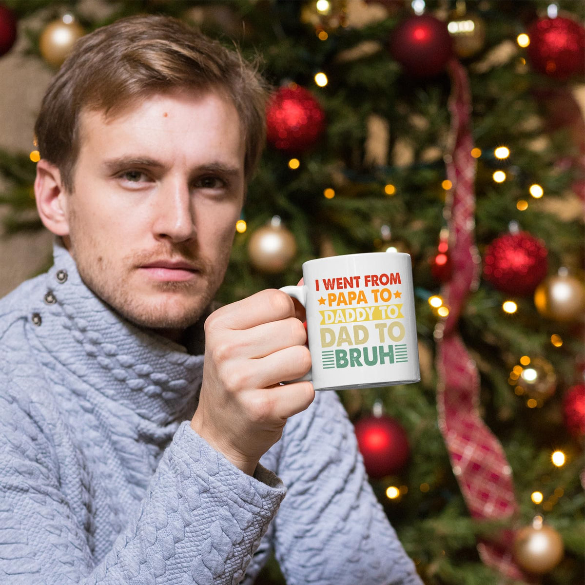 Man holding the Papa to Bruh mug in front of a Christmas tree