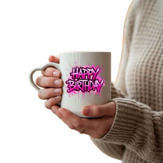 Hands holding the heart-handle mug with hot pink graffiti “Happy Birthday” lettering