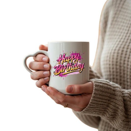 Hands holding the heart-handle mug with pink and yellow script “Happy Birthday” lettering