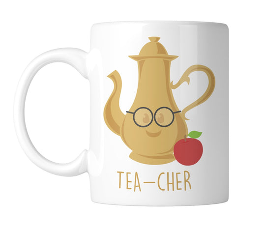 White mug with a gold teapot wearing glasses, an apple and “Tea-Cher”, handle on the left