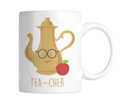 White mug with a gold teapot wearing glasses, an apple and “Tea-Cher”, handle on the right