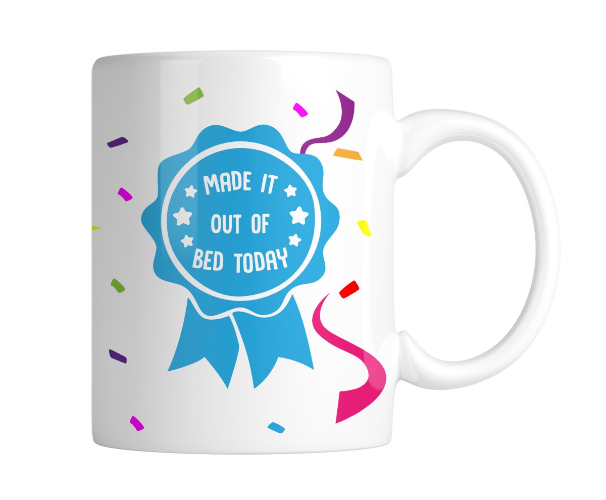 White mug with a blue award rosette that reads “Made It Out of Bed Today”, handle on the right