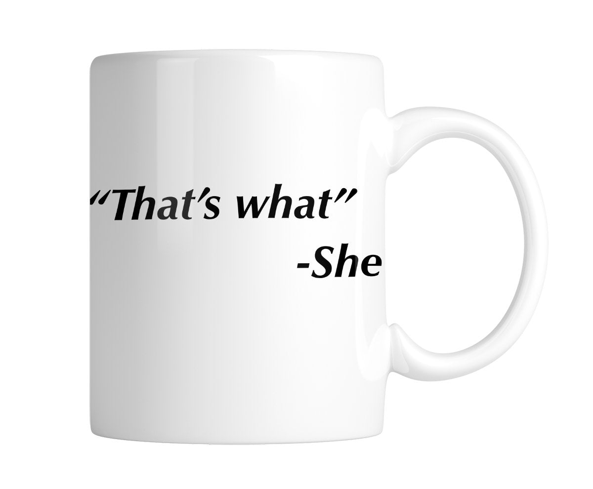 White mug printed with “That's what” – She in black italic text, handle on the right