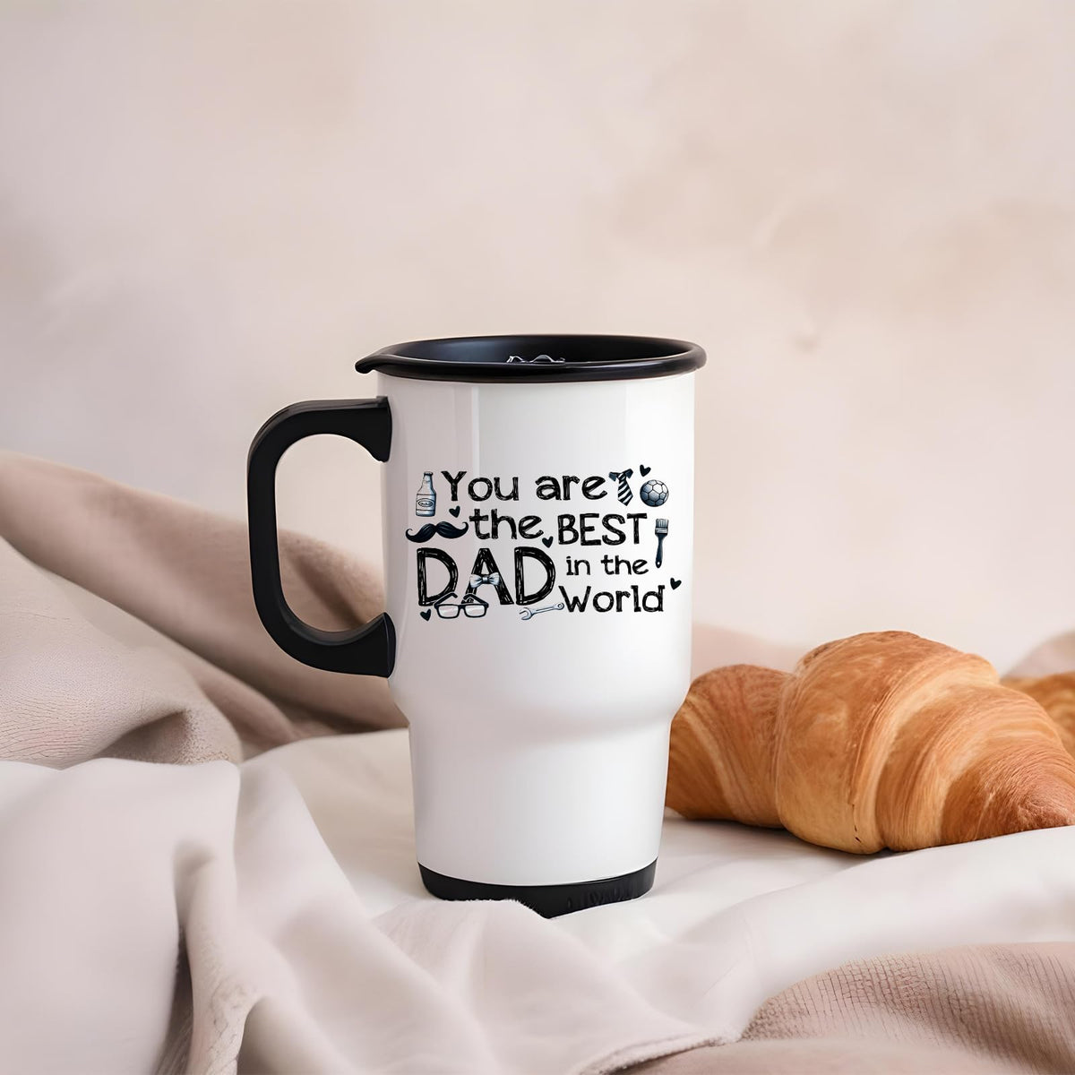 Best Dad in the World sketch travel mug on a soft blanket beside a croissant