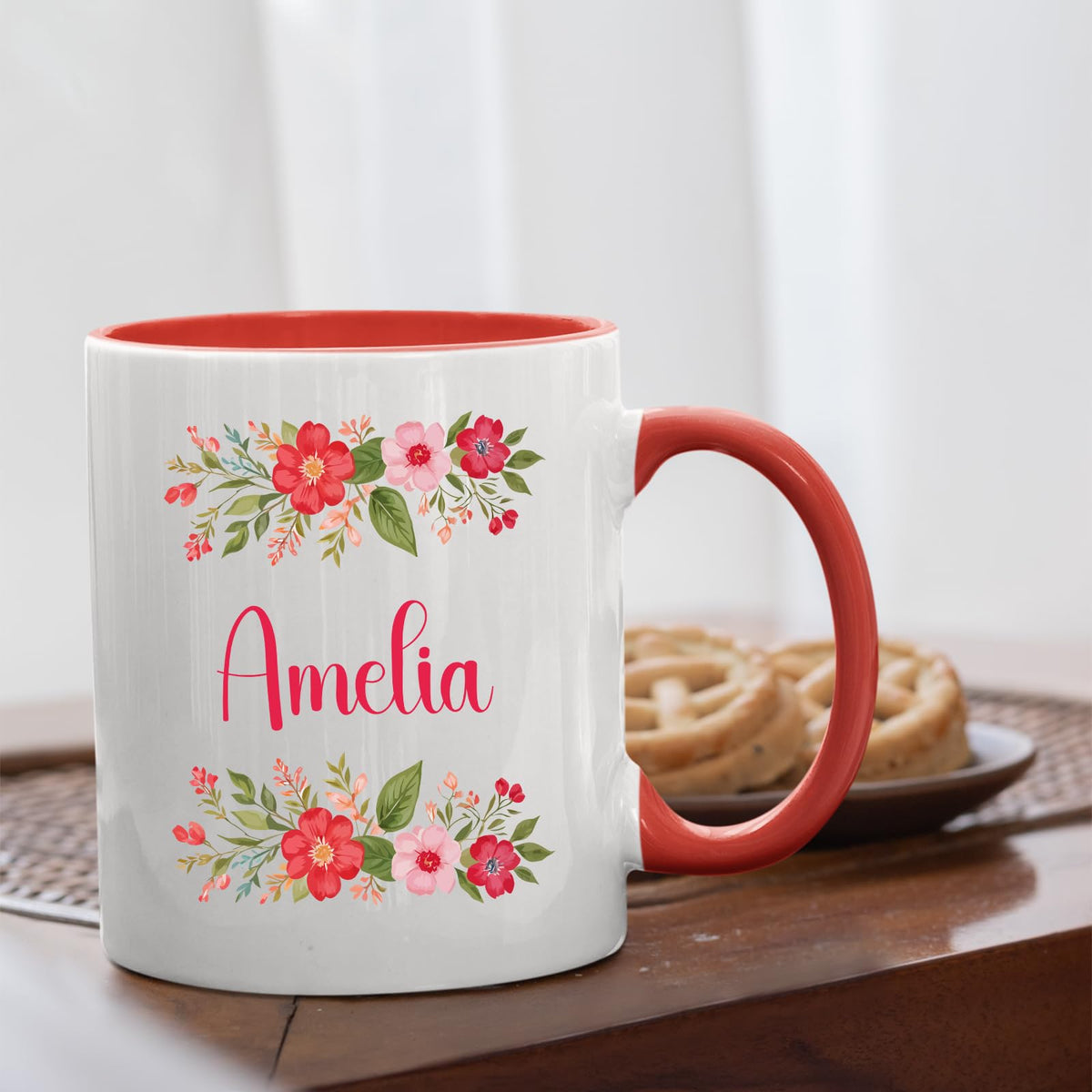 Red handle mug with a red flower border around an example name on a table