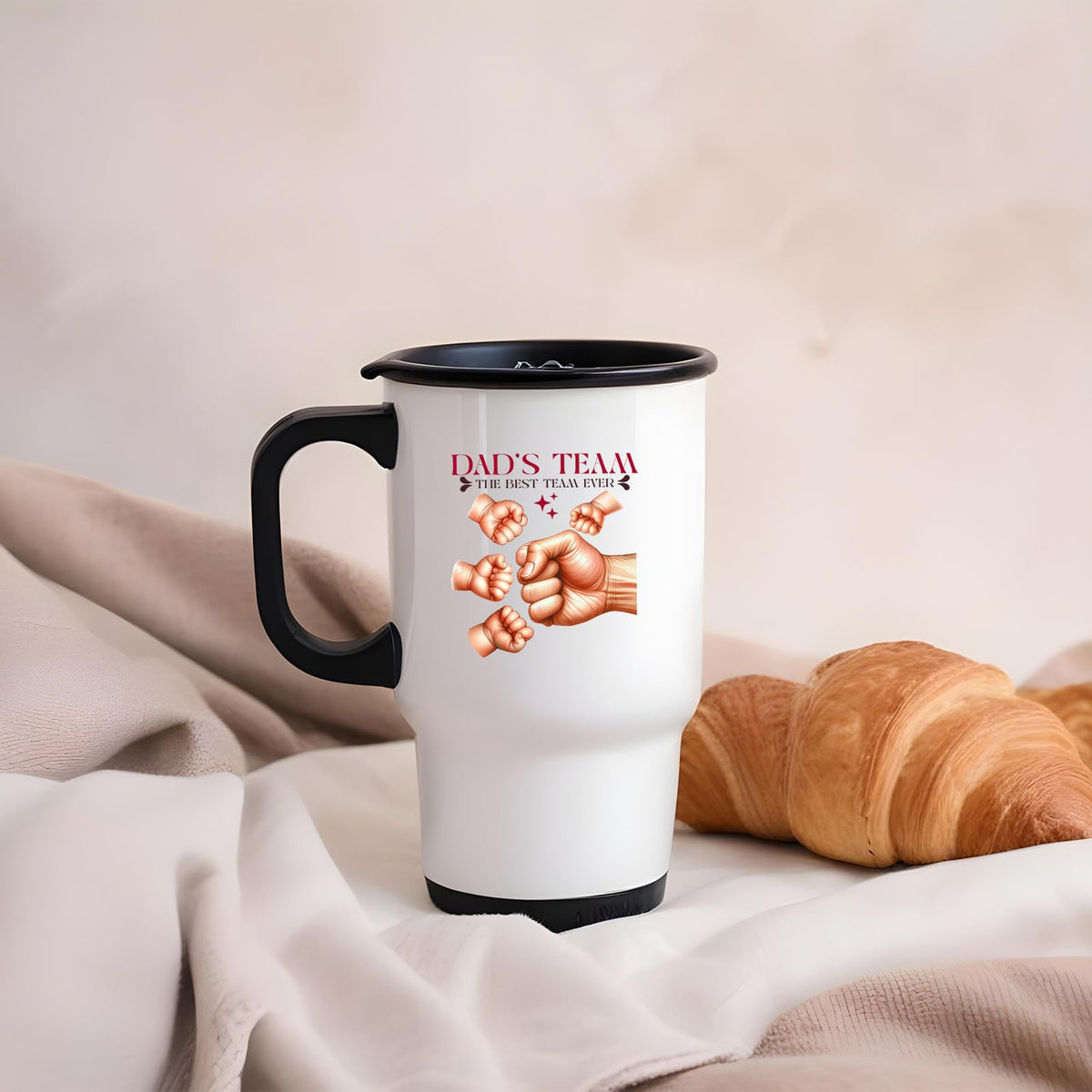 Dad’s Team fist bump travel mug on a soft blanket beside a croissant