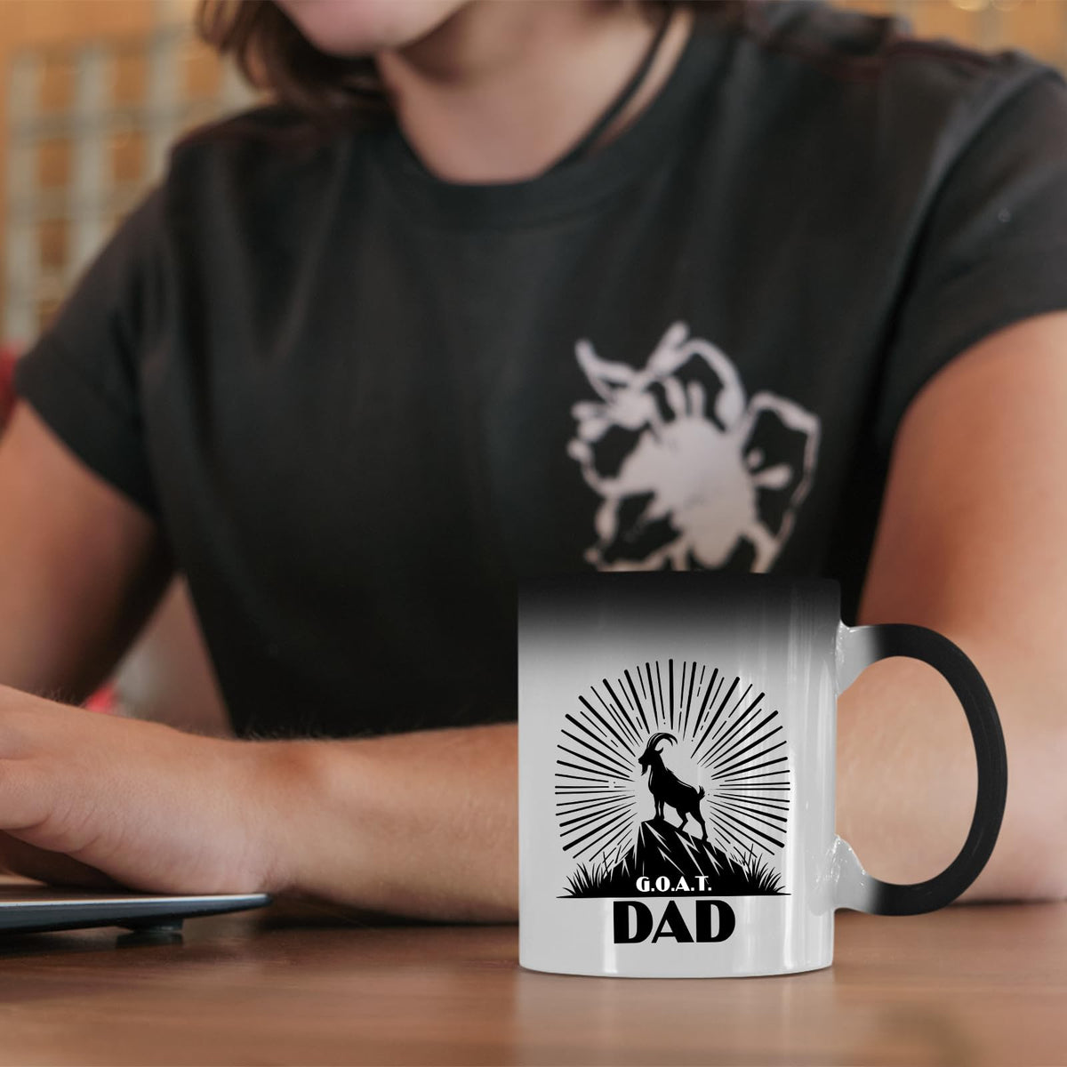 GOAT Dad colour changing mug on a desk beside a laptop