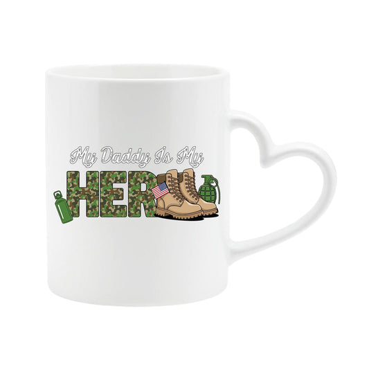 White heart-handle mug with “My Daddy is my hero” in camo lettering with army boots and a flag
