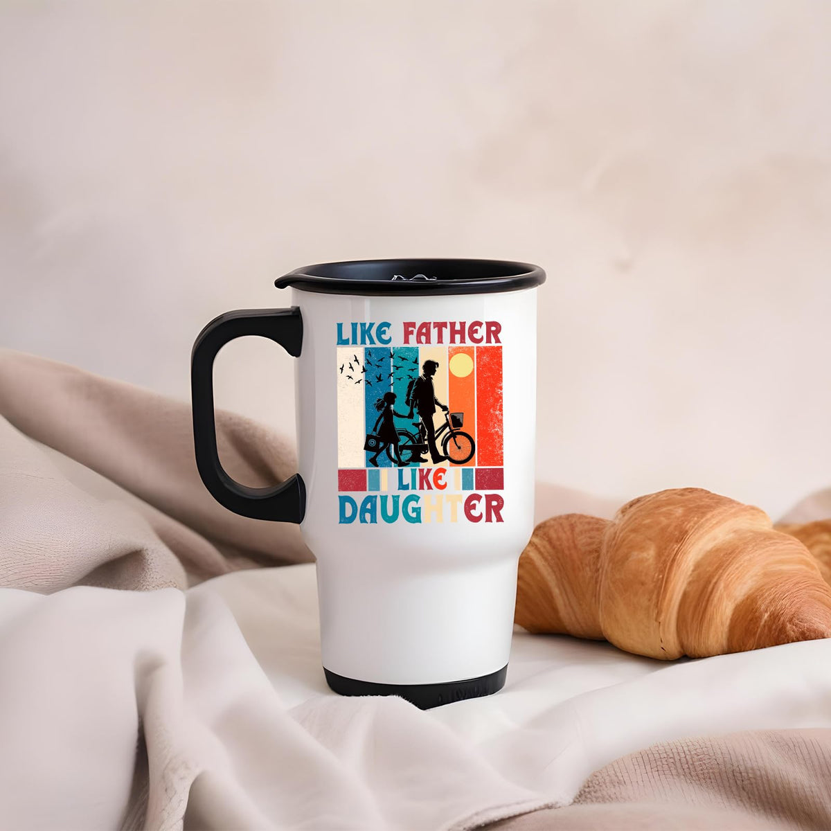 Like Father Like Daughter travel mug on a soft blanket beside a croissant