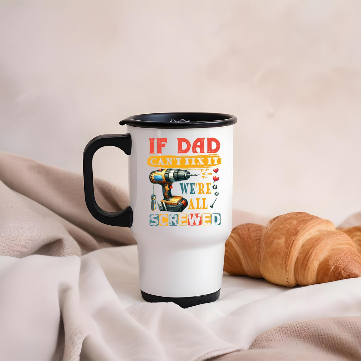 If Dad Can’t Fix It travel mug on a soft blanket beside a croissant