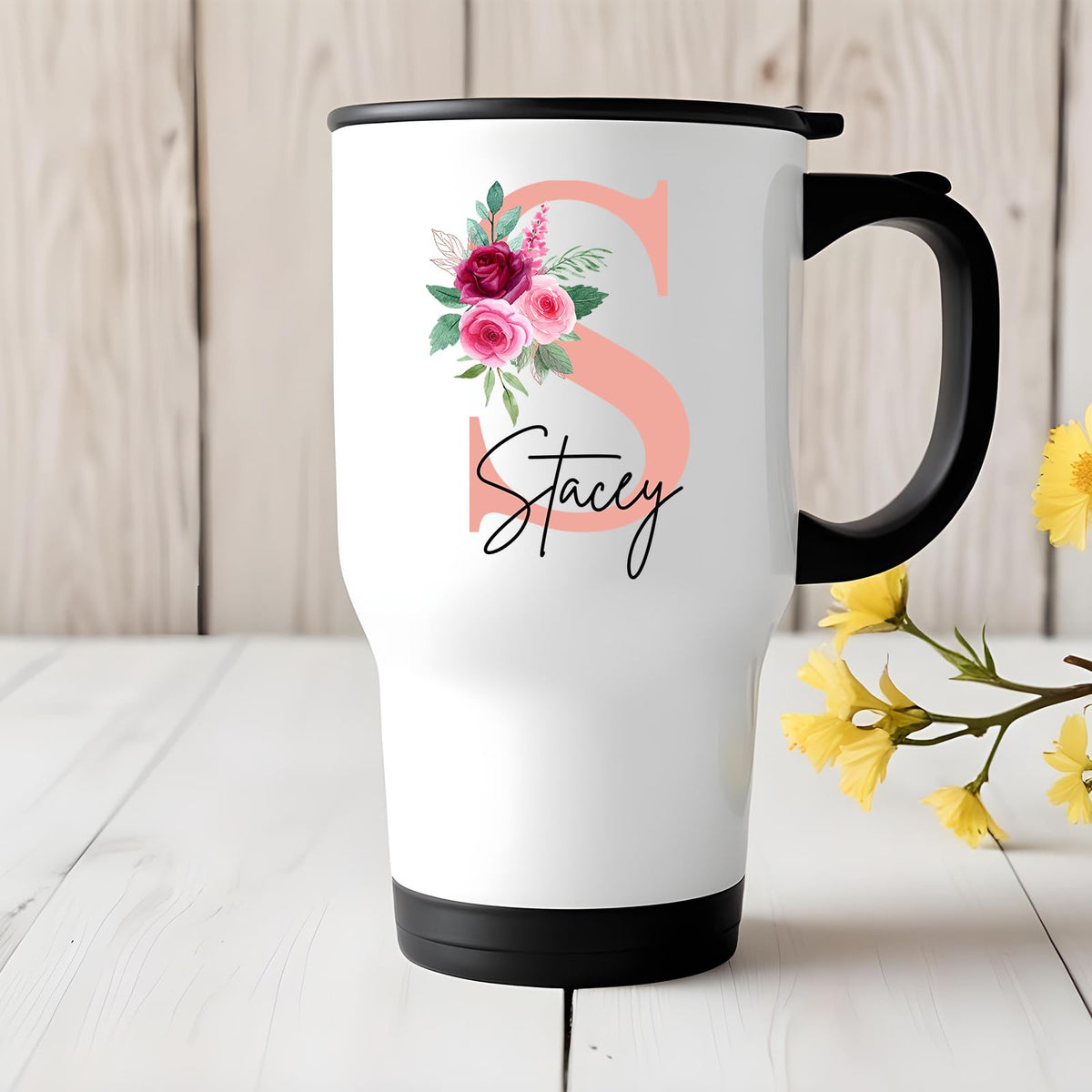 Travel mug with a blush pink initial with roses and an example name on a white table with yellow flowers