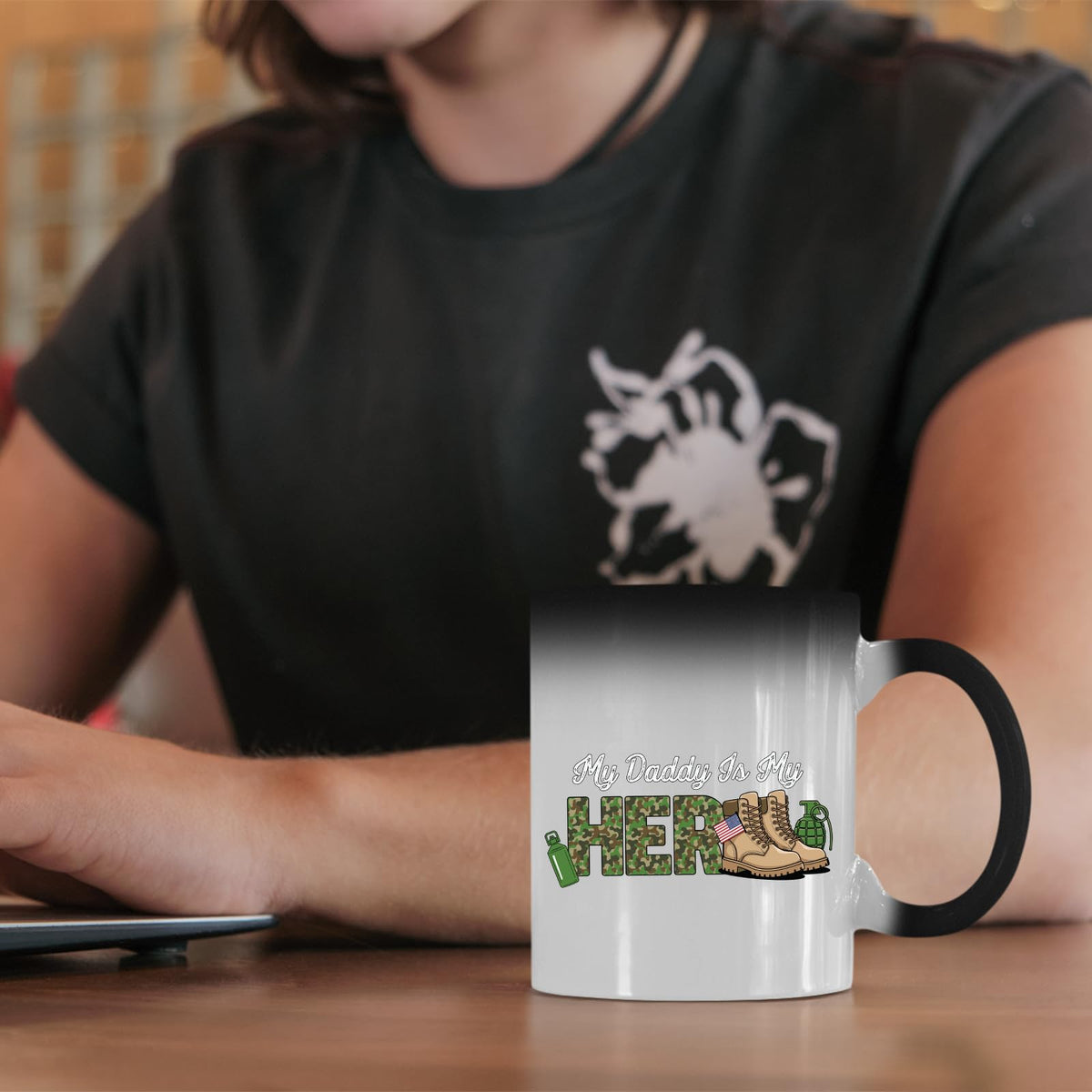 My Daddy Is My Hero military colour changing mug on a desk beside a laptop