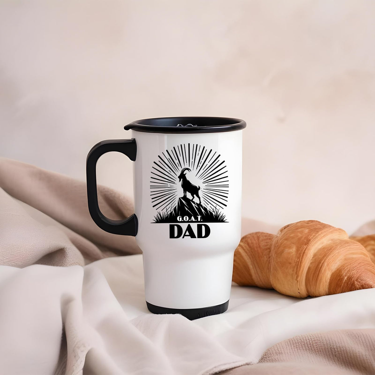 GOAT Dad travel mug on a soft blanket beside a croissant