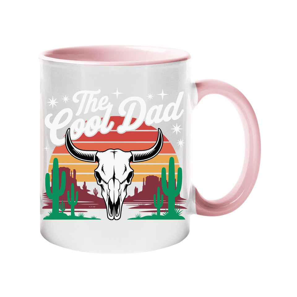 Colour handle mug with a bull skull, cacti and a retro desert sunset with “The Cool Dad” – light pink handle and inside