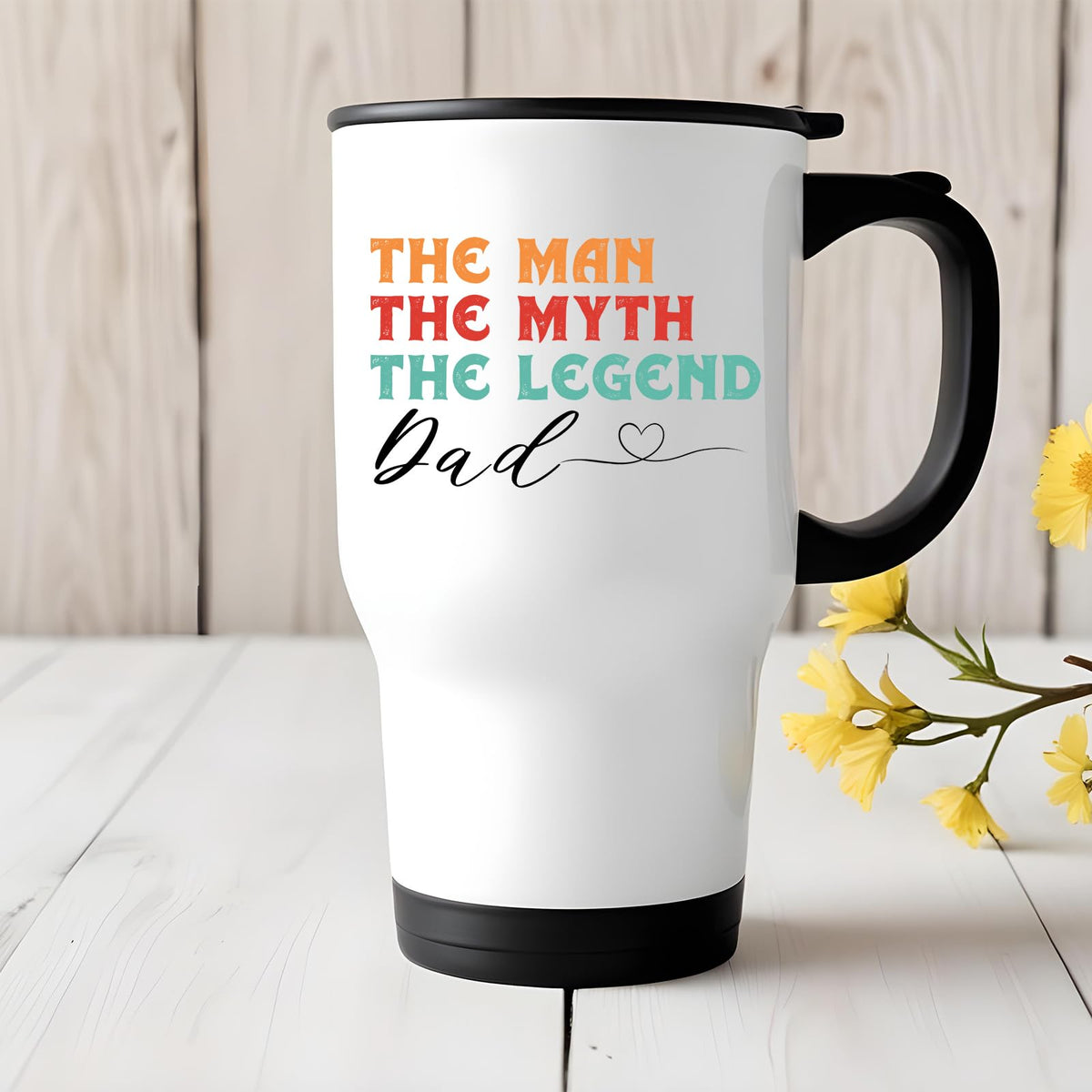 The Man the Myth Dad travel mug on a white wooden table with yellow flowers