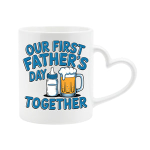 White heart-handle mug with a baby bottle and a pint of beer with “Our first Father’s Day together” in blue
