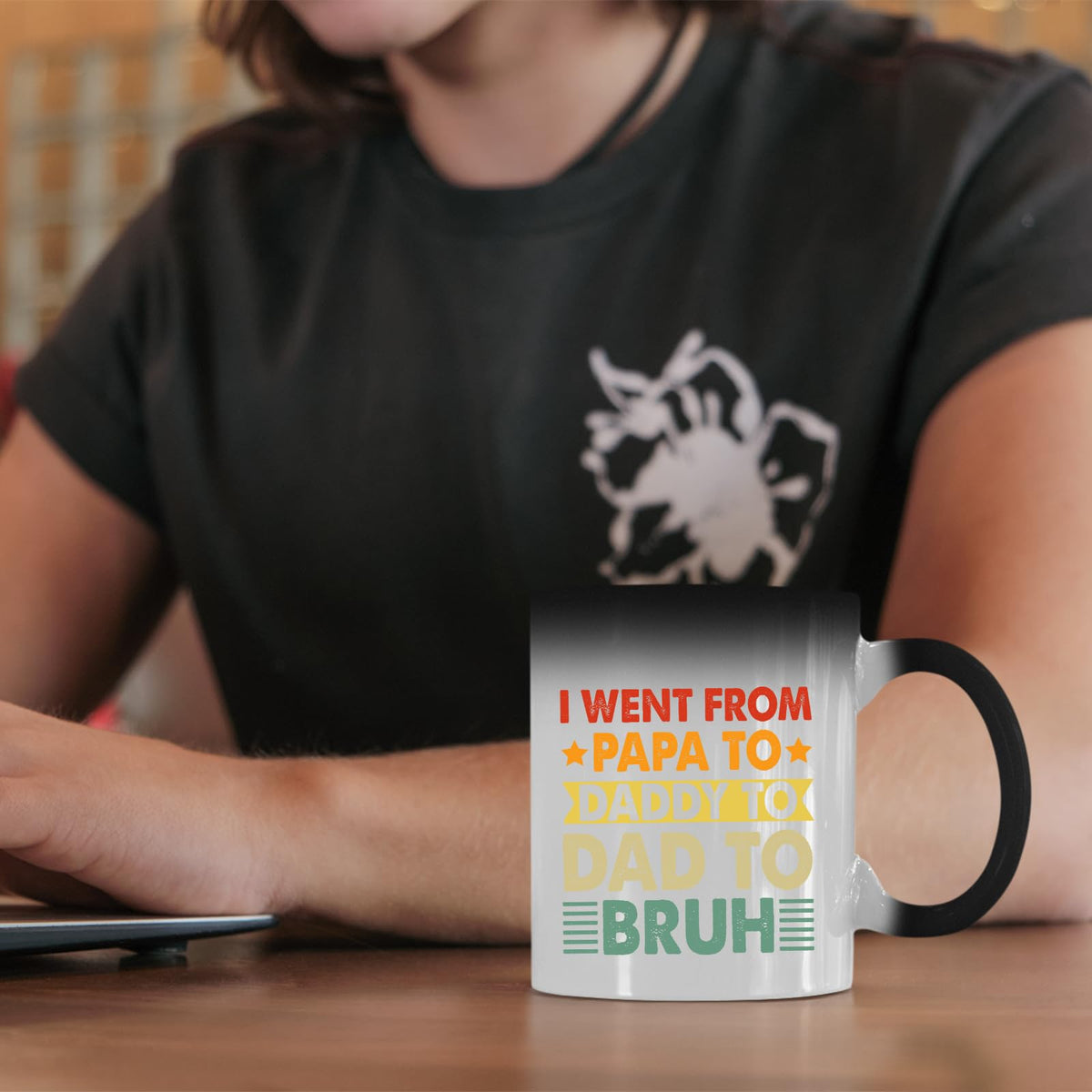 Papa to Bruh colour changing mug on a desk beside a laptop