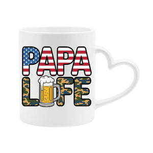 White heart-handle mug with “Papa” in stars and stripes over camo “Life” with a frothy beer