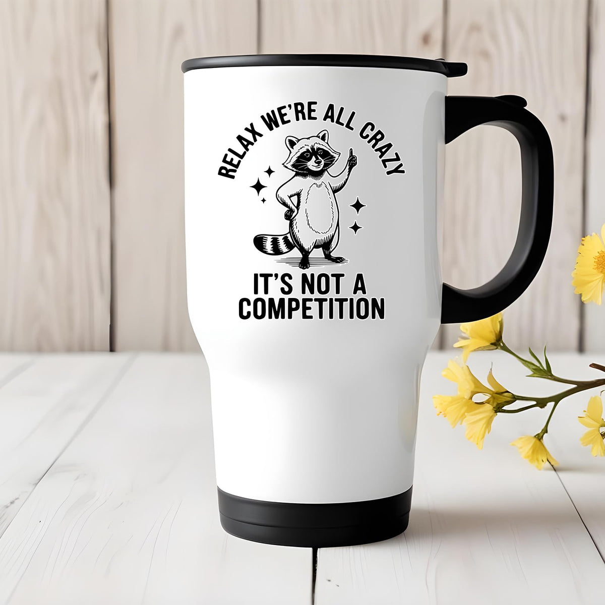 Relax We’re All Crazy raccoon travel mug on a white wooden table with yellow flowers