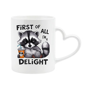 White heart-handle mug with a grumpy raccoon with a skull cup and “First of all, I’m a delight”