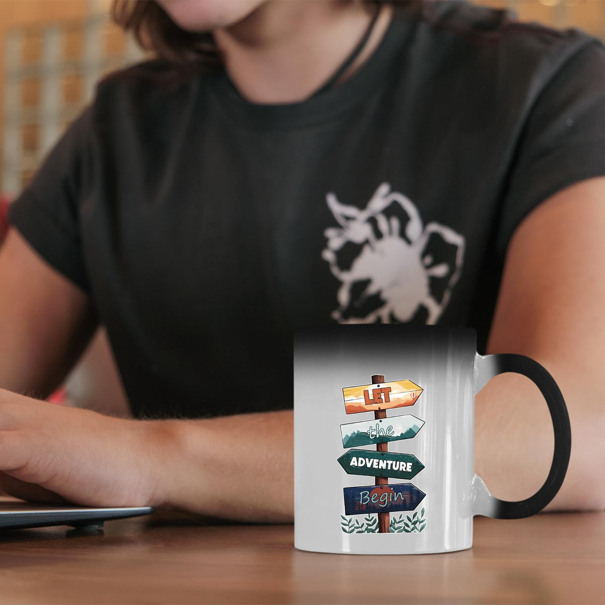 Let the Adventure Begin colour changing mug on a desk beside a laptop