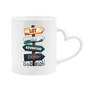 White heart-handle mug with wooden signposts spelling out “Let the adventure begin”