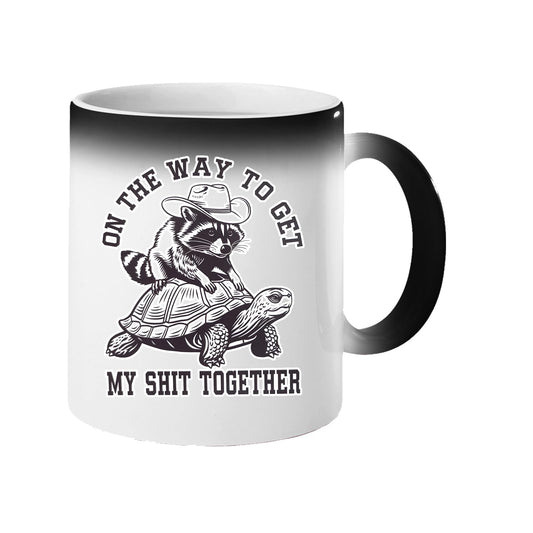 Colour changing mug revealing a raccoon in a cowboy hat riding a tortoise and “On the way to get my shit together”