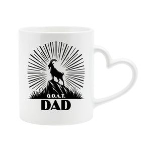 White heart-handle mug with a mountain goat on a peak with a sunburst and “G.O.A.T. Dad”