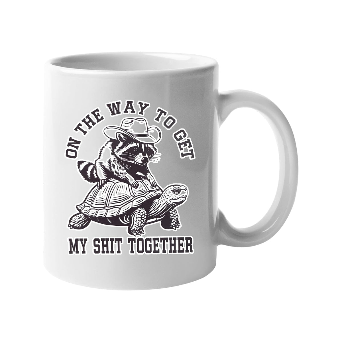 White mug with a raccoon in a cowboy hat riding a tortoise and “On the way to get my shit together”