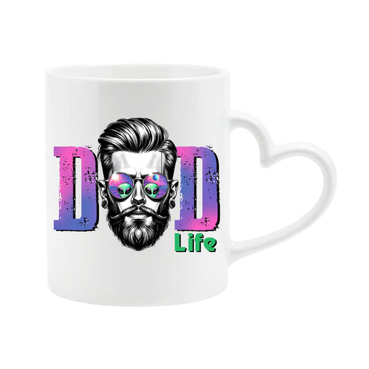 White heart-handle mug with a bearded dad in sunglasses between pink “DAD” letters signed “Life”