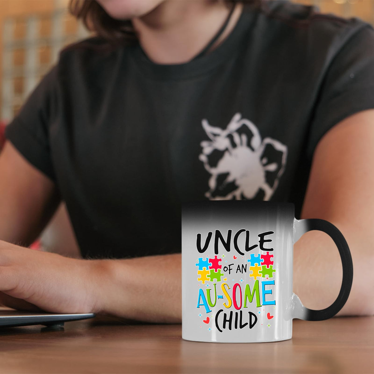 Uncle of an Au-Some Child colour changing mug on a desk beside a laptop
