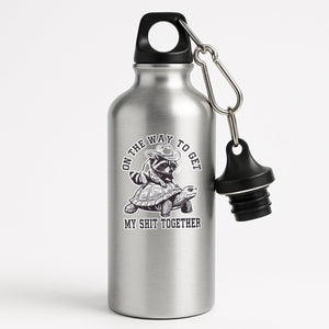 Silver aluminium water bottle with a raccoon in a cowboy hat riding a tortoise and “On the way to get my shit together”