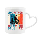 White heart-handle mug with a dad and daughter with a bike in silhouette over retro stripes and “Like father, like daughter”