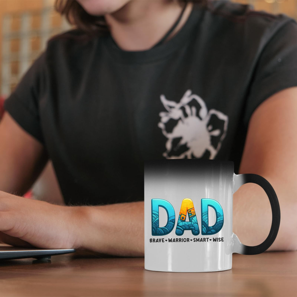 DAD Brave Warrior colour changing mug on a desk beside a laptop