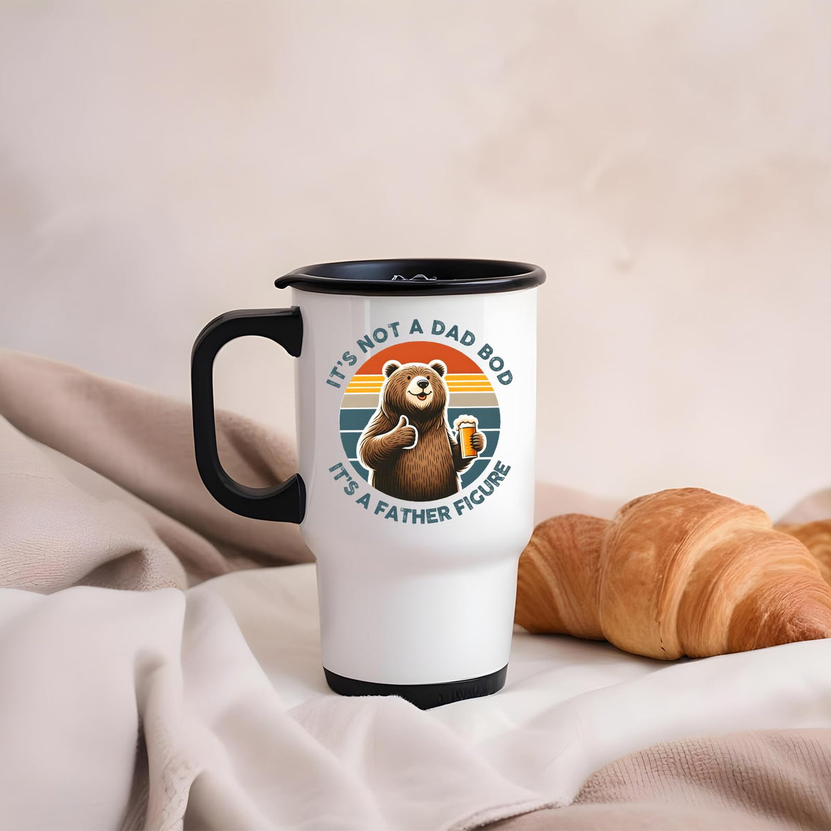 Dad Bod bear travel mug on a soft blanket beside a croissant