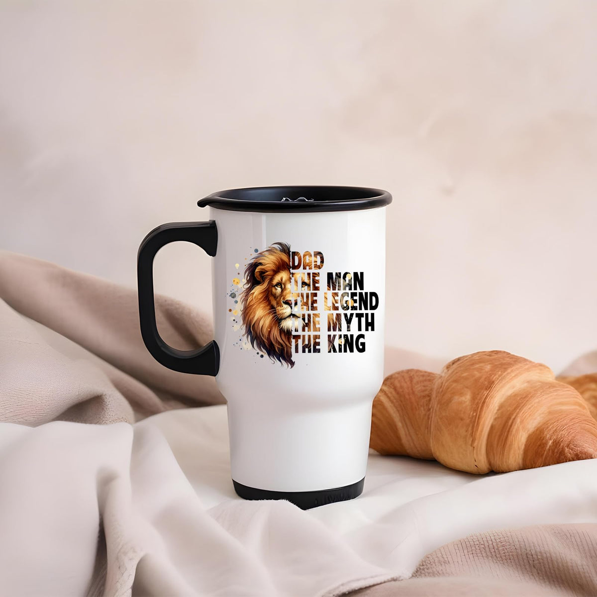Dad the King lion travel mug on a soft blanket beside a croissant