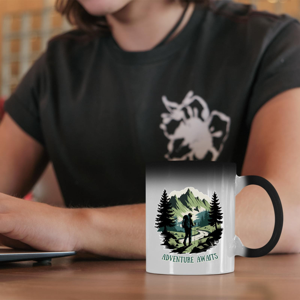 Adventure Awaits hiker colour changing mug on a desk beside a laptop
