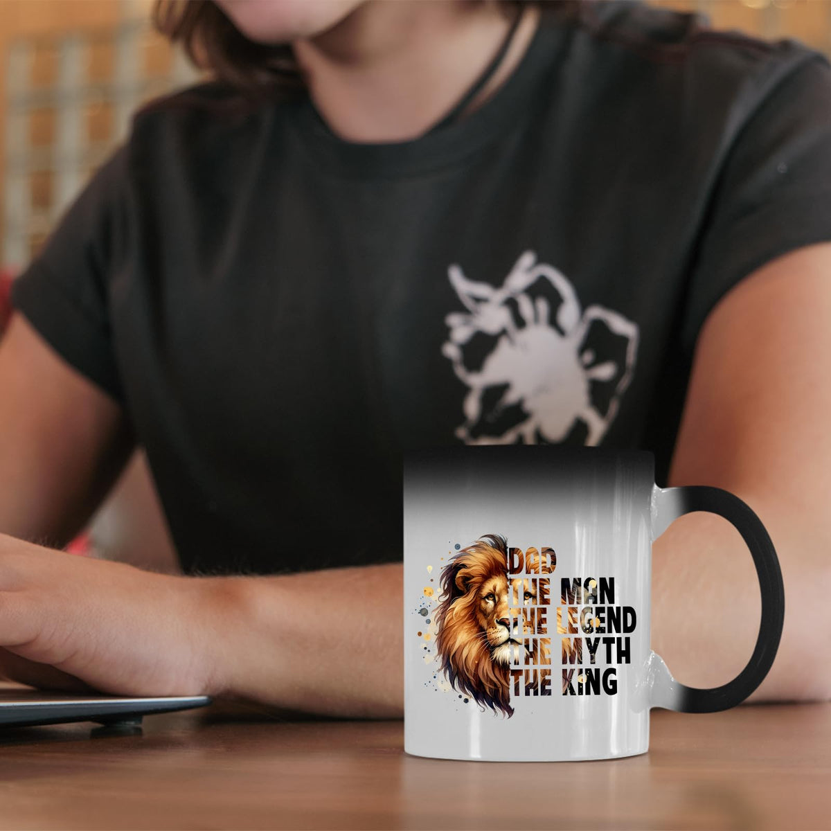 Dad the King lion colour changing mug on a desk beside a laptop