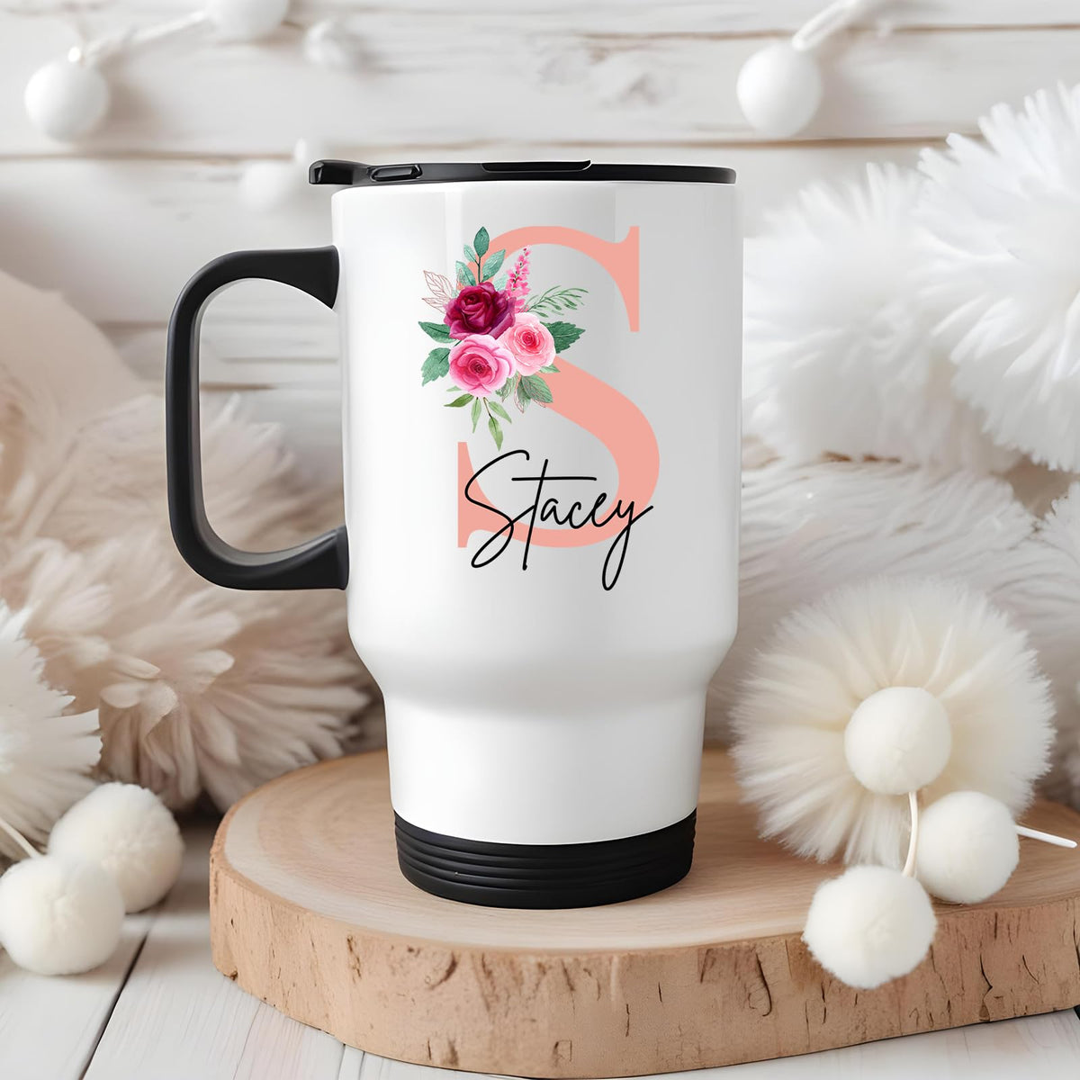 Travel mug with a blush pink initial with roses and an example name on a wooden board with white pompoms