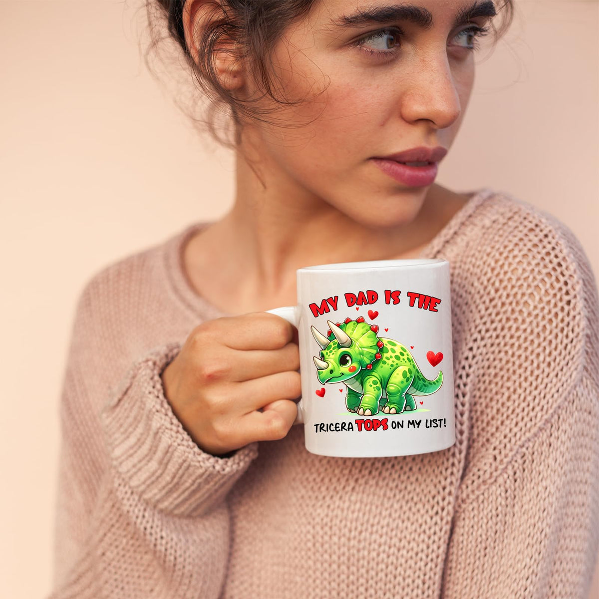 Woman in a pink jumper holding the Triceratops dad mug