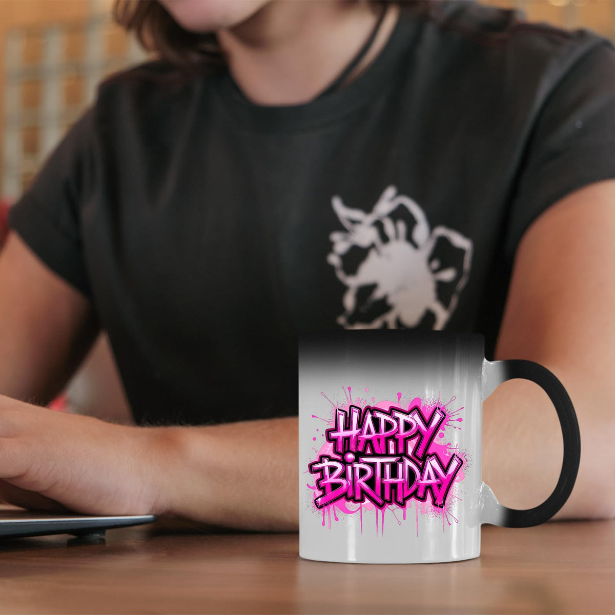 Happy Birthday pink drip colour changing mug on a desk beside a laptop