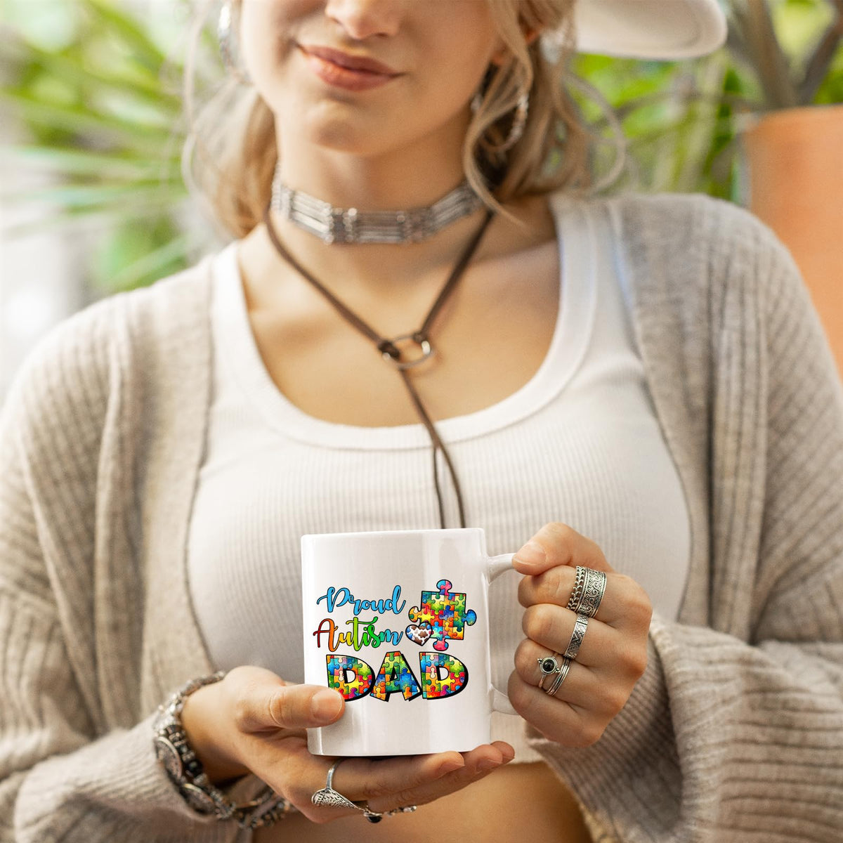 Woman in a cardigan holding the Proud Autism Dad mug