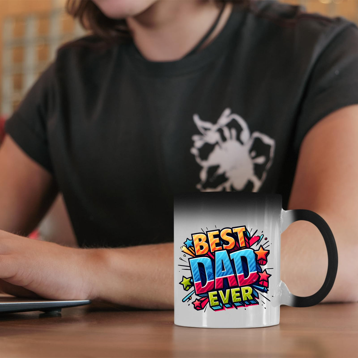 Best Dad Ever comic colour changing mug on a desk beside a laptop
