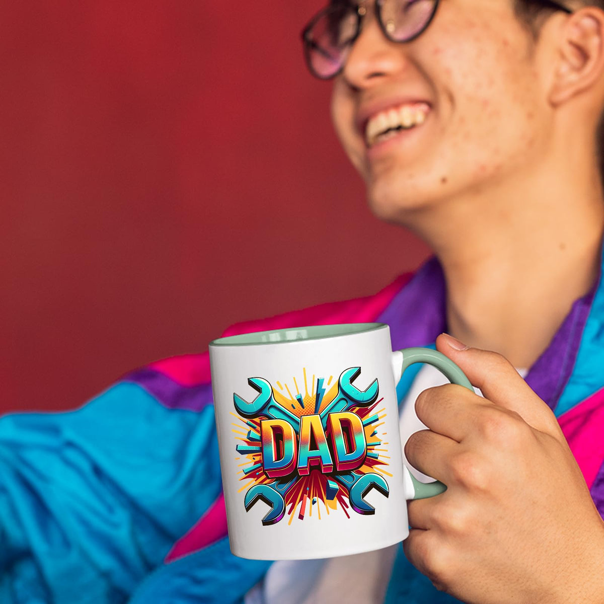Smiling person in a colourful jacket holding the DAD spanners mug with a light green handle