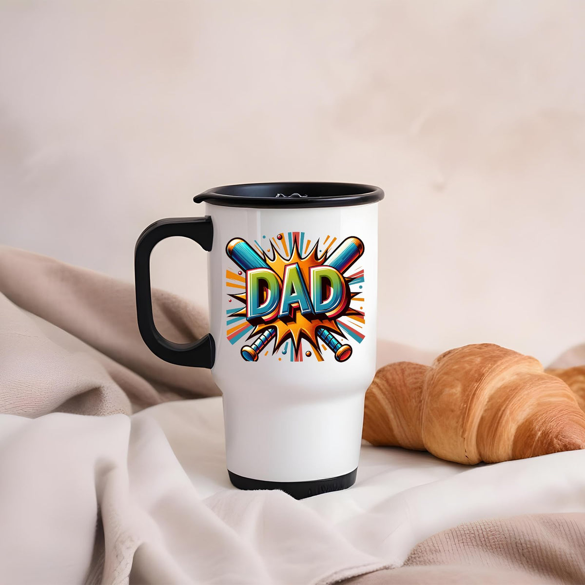 DAD baseball bats travel mug on a soft blanket beside a croissant