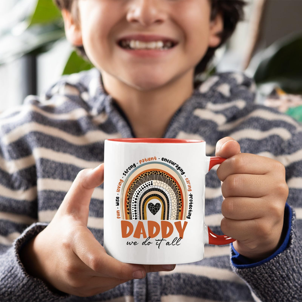 Smiling child holding the Daddy boho rainbow mug with a red handle
