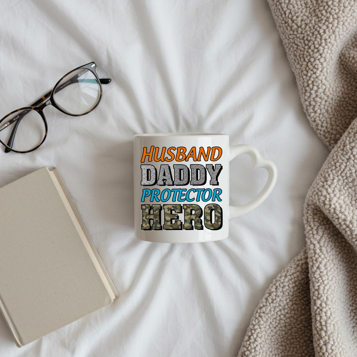 Husband Daddy Protector Hero camo heart-handle mug on a bed beside glasses and a book
