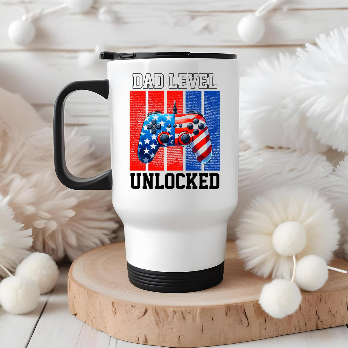 Dad Level Unlocked travel mug on a wooden slice with white pom-poms