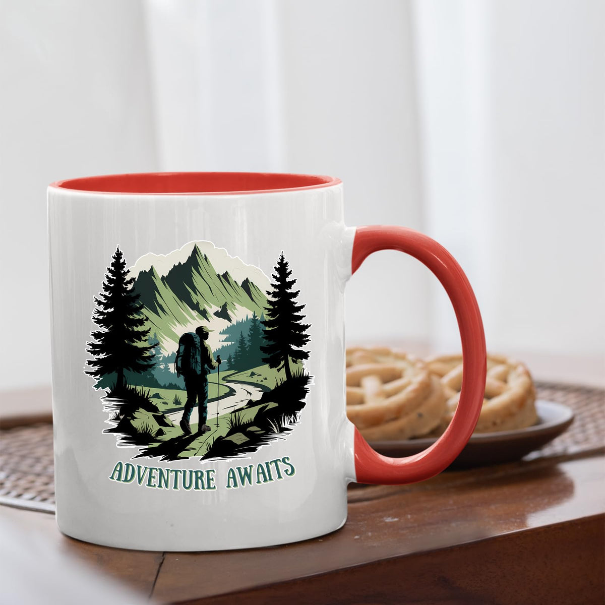 Adventure Awaits hiker mug with a red handle beside biscuits